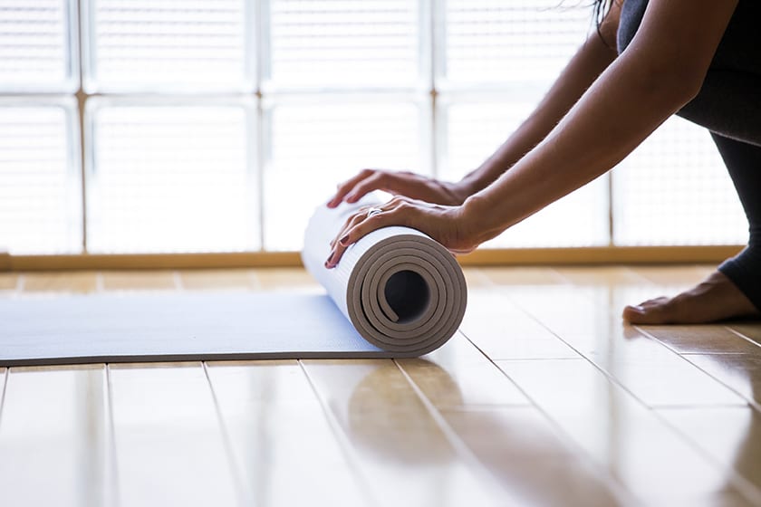 Woman rolling up a yoga mat at a pilates studio