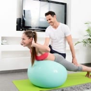 Male private pilates instructor working with female in home