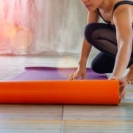Woman rolling up a yoga mat at a pilates studio